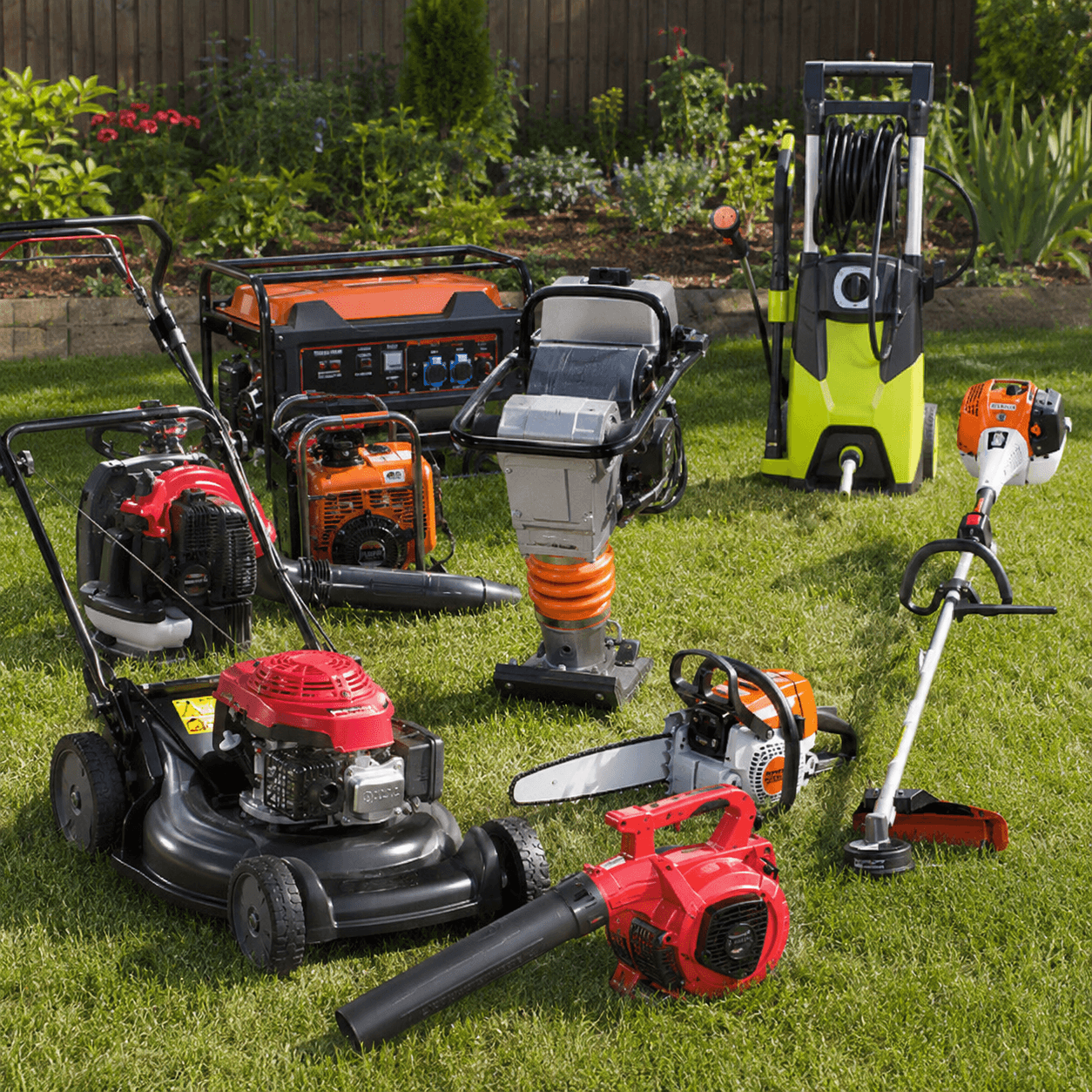 Assorted outdoor power equipment including a lawnmower, chainsaw, and generator on a green lawn.